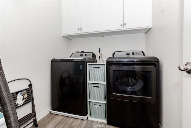 washroom featuring cabinet space, independent washer and dryer, light wood-style flooring, and baseboards