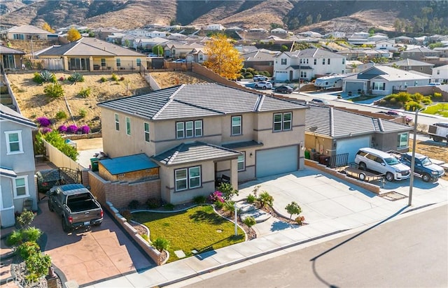 view of front of house featuring driveway, stucco siding, a garage, a tile roof, and a residential view