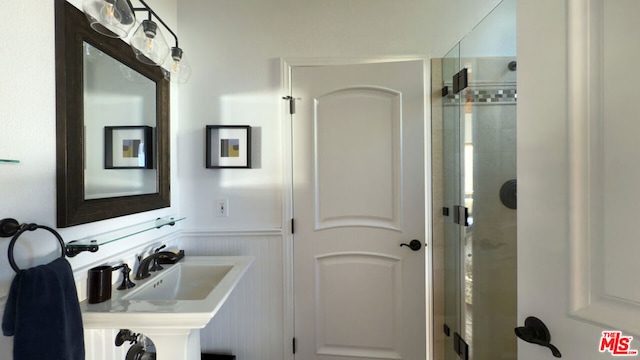 bathroom with a shower with shower door and sink