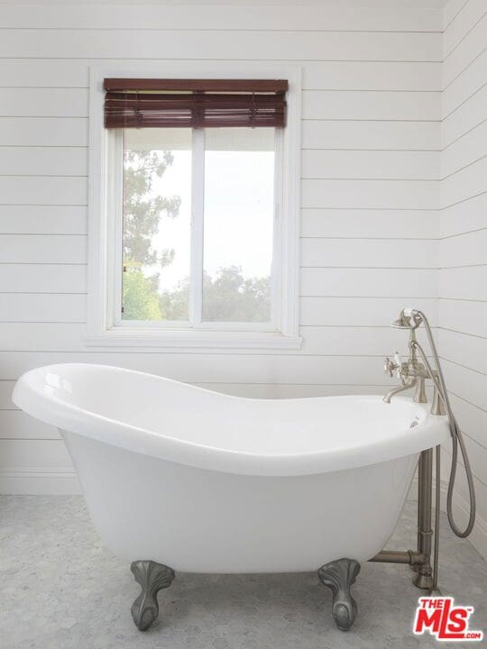 bathroom featuring a bathing tub, plenty of natural light, and wooden walls