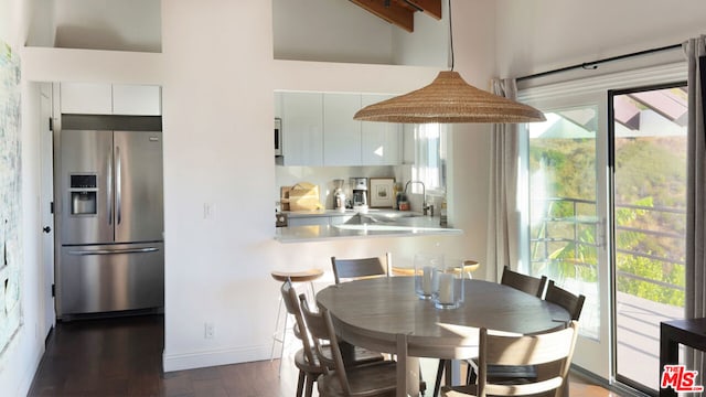 dining area featuring beamed ceiling, dark hardwood / wood-style floors, and sink