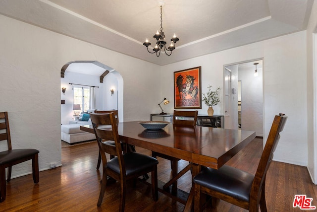 dining room featuring a chandelier, dark hardwood / wood-style floors, and a raised ceiling