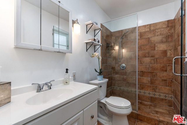 bathroom featuring a shower with shower door, toilet, and vanity