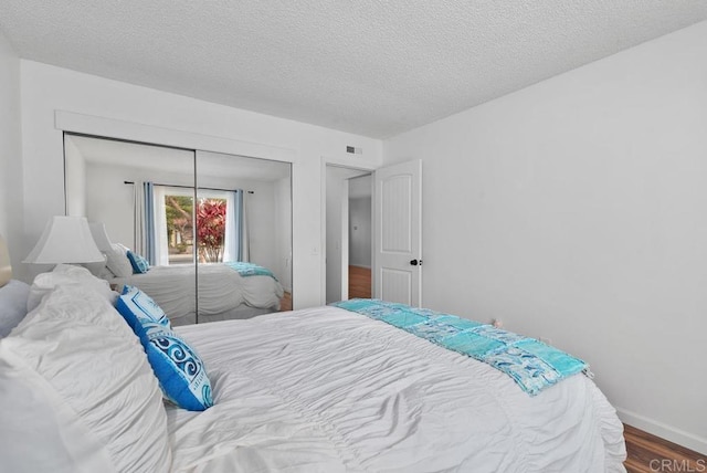 bedroom with wood-type flooring, a textured ceiling, and a closet