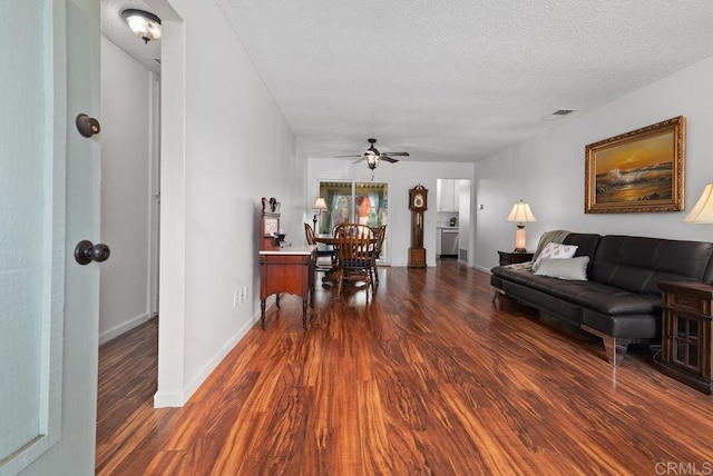 living room featuring dark hardwood / wood-style flooring, ceiling fan, and a textured ceiling