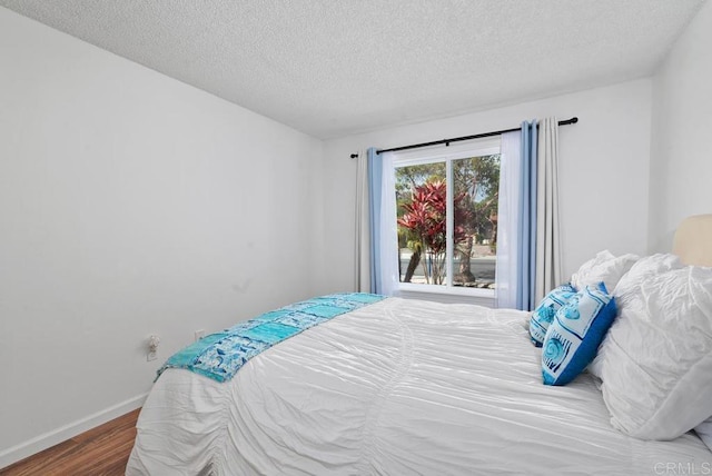 bedroom featuring wood-type flooring, a textured ceiling, and access to outside