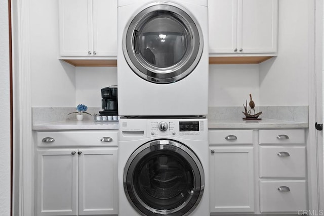 laundry area with cabinets and stacked washing maching and dryer