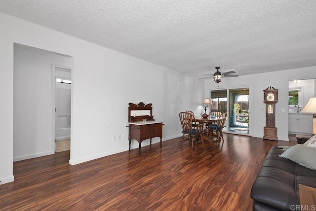 living room with ceiling fan, dark wood-type flooring, and a textured ceiling