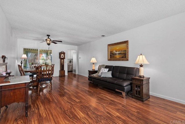 living room with ceiling fan, dark wood-type flooring, and a textured ceiling