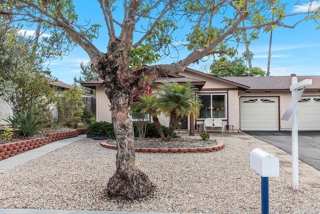 view of front of home with a garage, aphalt driveway, and stucco siding