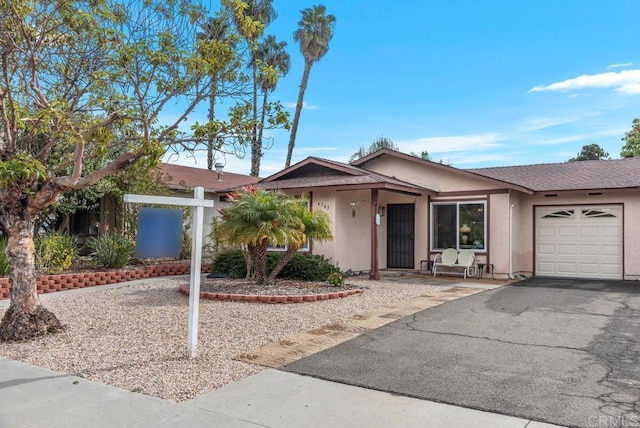 mid-century modern home featuring driveway, an attached garage, and stucco siding