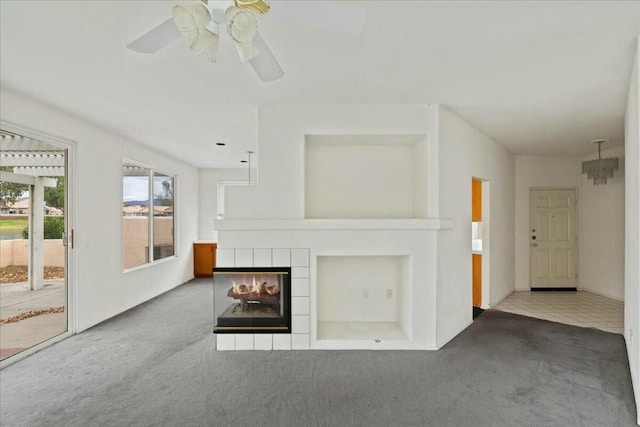 unfurnished living room with carpet flooring, a tile fireplace, and ceiling fan