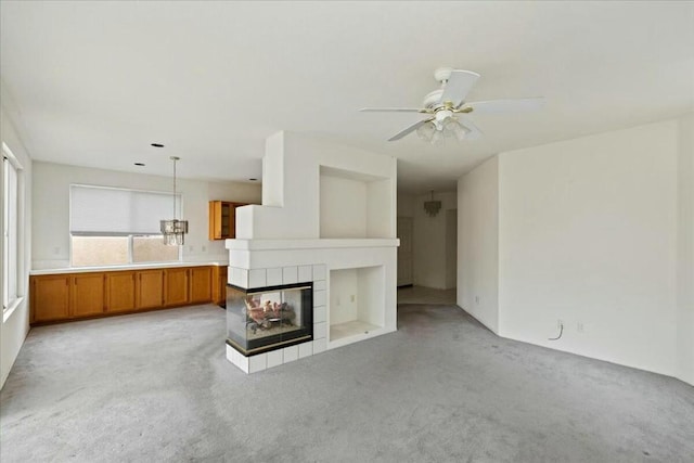 unfurnished living room featuring a multi sided fireplace, ceiling fan, and light carpet