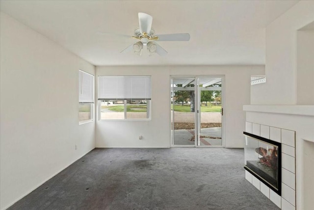 unfurnished living room with carpet floors, ceiling fan, and a tiled fireplace