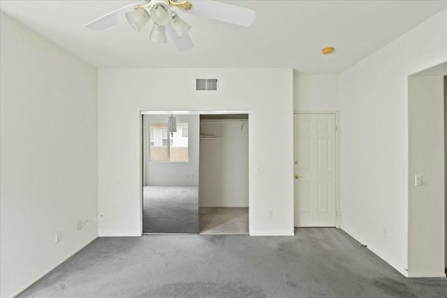 unfurnished bedroom featuring ceiling fan, dark carpet, and a closet