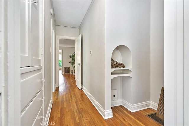 corridor featuring built in shelves and light hardwood / wood-style flooring