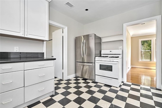 kitchen featuring white range with gas cooktop, stainless steel fridge, white cabinets, and dark hardwood / wood-style floors