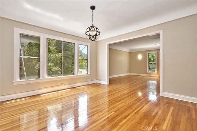 unfurnished room with an inviting chandelier and light hardwood / wood-style flooring