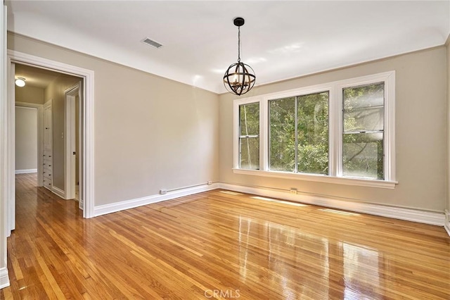 empty room with hardwood / wood-style flooring and a notable chandelier