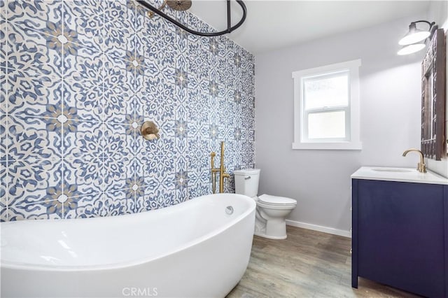 bathroom with a bathing tub, vanity, wood-type flooring, and toilet