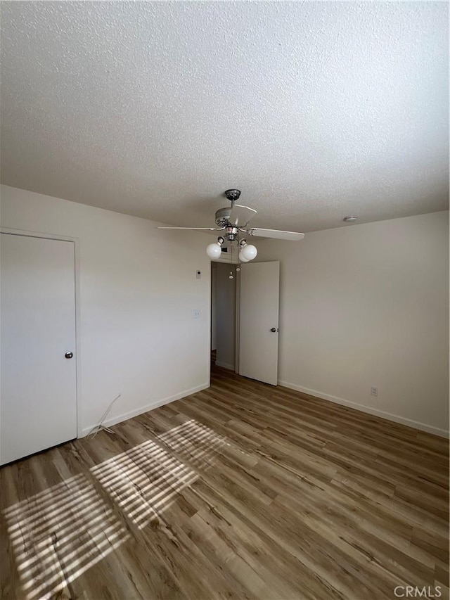 unfurnished room with baseboards, a textured ceiling, a ceiling fan, and wood finished floors