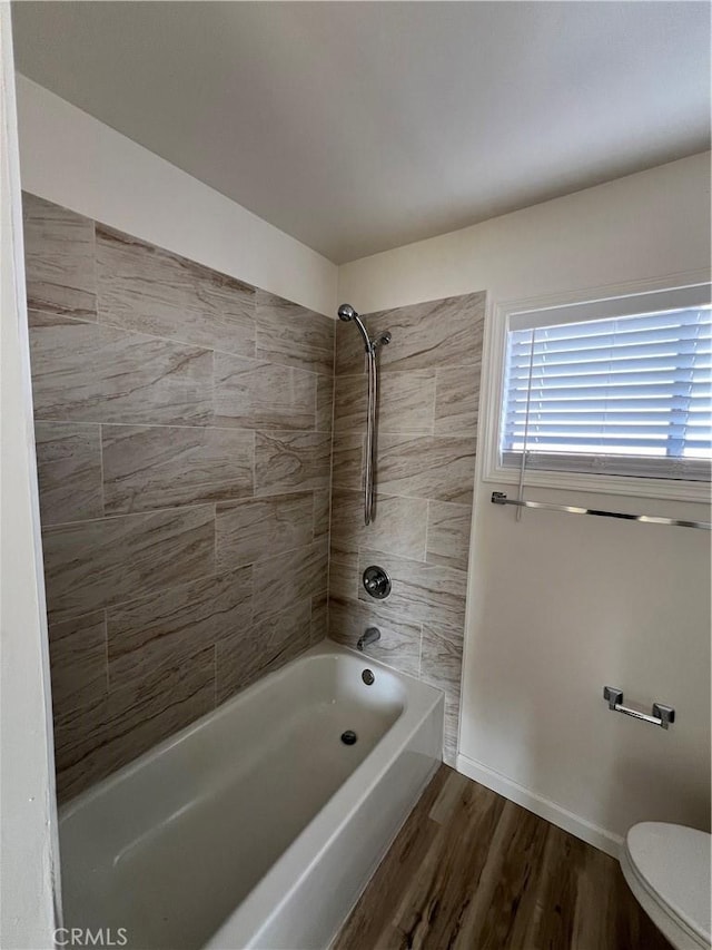 bathroom with shower / bathtub combination, wood finished floors, toilet, and baseboards