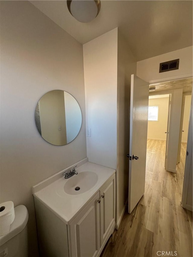 bathroom featuring visible vents, vanity, toilet, and wood finished floors