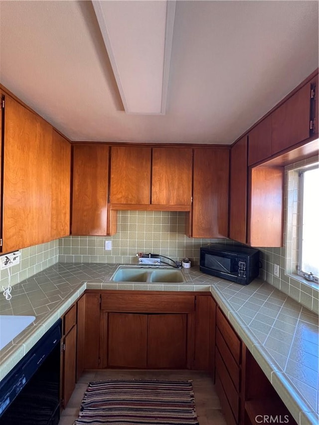 kitchen featuring black appliances, tasteful backsplash, tile counters, and brown cabinetry