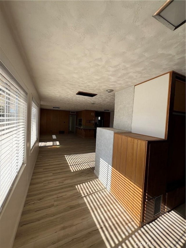 interior space with a textured ceiling, baseboards, and wood finished floors