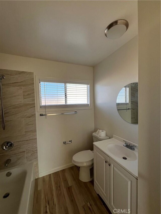 full bathroom with toilet, wood finished floors, vanity, baseboards, and washtub / shower combination