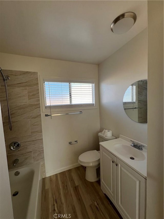 bathroom with baseboards, toilet, wood finished floors, vanity, and washtub / shower combination