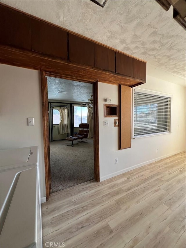 interior space featuring a textured ceiling, baseboards, washer / dryer, and light wood-style floors