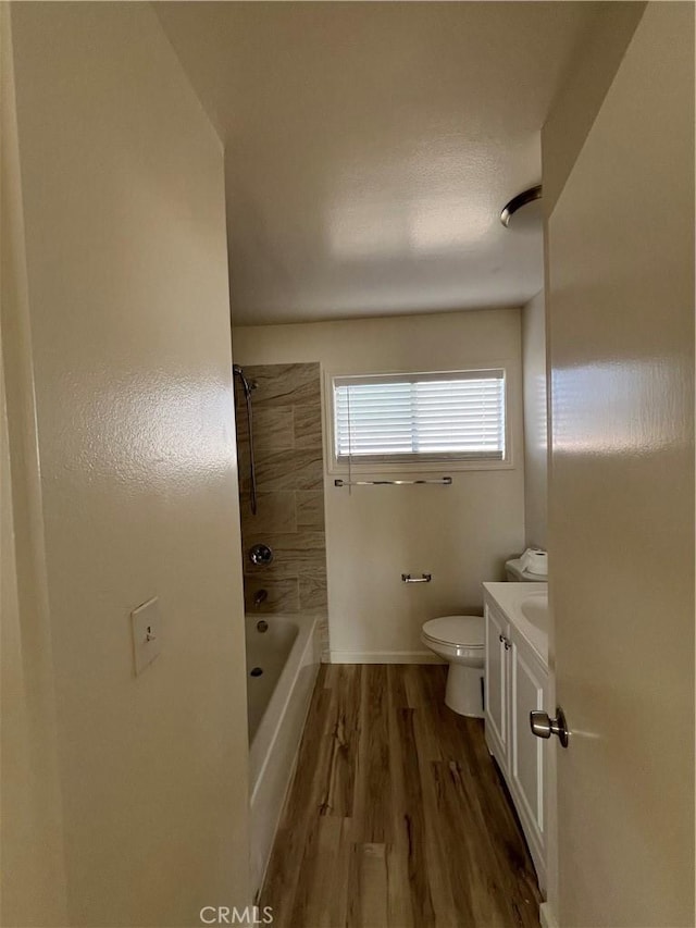 bathroom featuring toilet, vanity, shower / tub combination, wood finished floors, and baseboards