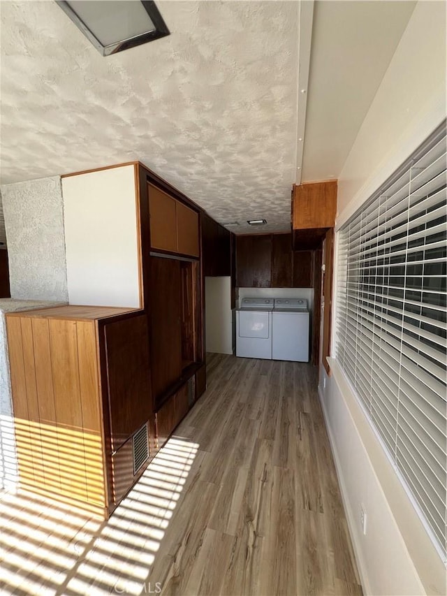 kitchen with a textured ceiling, washer and clothes dryer, and wood finished floors