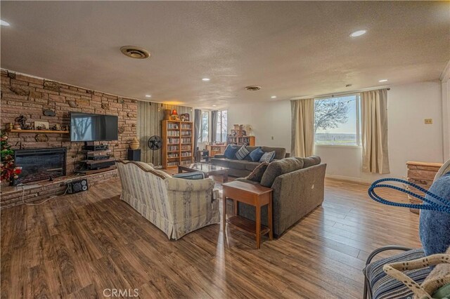 living room with a fireplace, a healthy amount of sunlight, a textured ceiling, and wood-type flooring