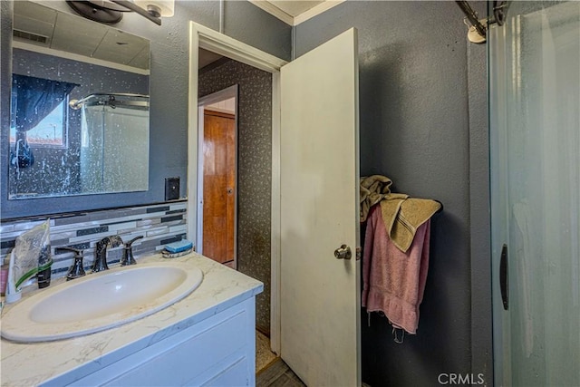 bathroom featuring tasteful backsplash, a shower, vanity, and ornamental molding