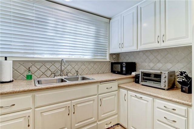 kitchen featuring tasteful backsplash, white cabinetry, and sink