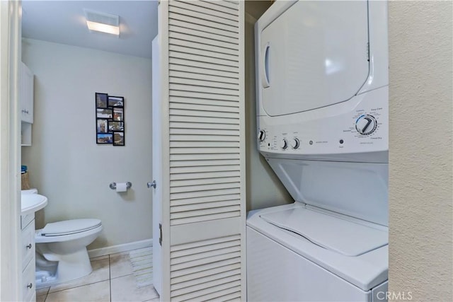 laundry area featuring light tile patterned flooring and stacked washing maching and dryer