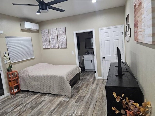 bedroom featuring hardwood / wood-style floors, ensuite bathroom, a wall unit AC, and ceiling fan