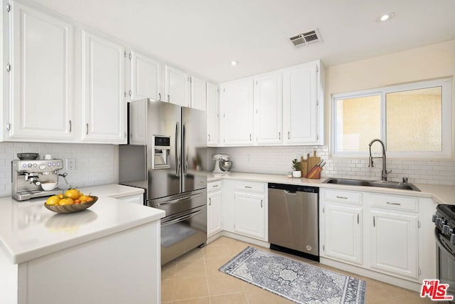 kitchen with tasteful backsplash, sink, white cabinets, and appliances with stainless steel finishes