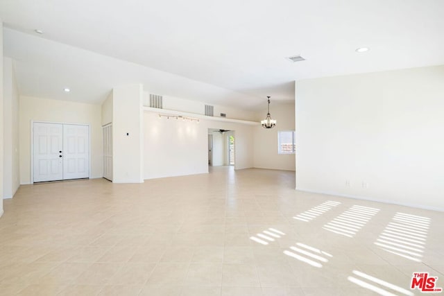 tiled empty room featuring a chandelier