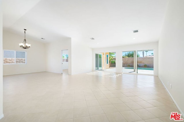 tiled empty room featuring an inviting chandelier and vaulted ceiling