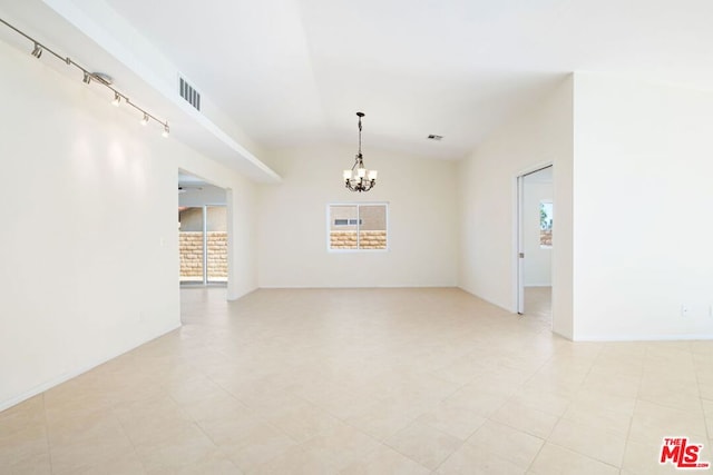 tiled empty room with track lighting, a chandelier, and lofted ceiling