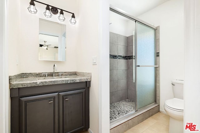 bathroom with ceiling fan, tile patterned flooring, toilet, a shower with door, and vanity