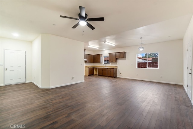 unfurnished living room featuring ceiling fan, sink, and dark wood-type flooring