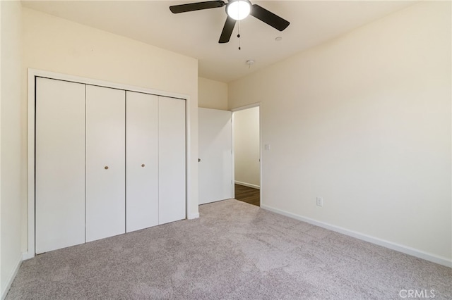 unfurnished bedroom with ceiling fan, light carpet, and a closet