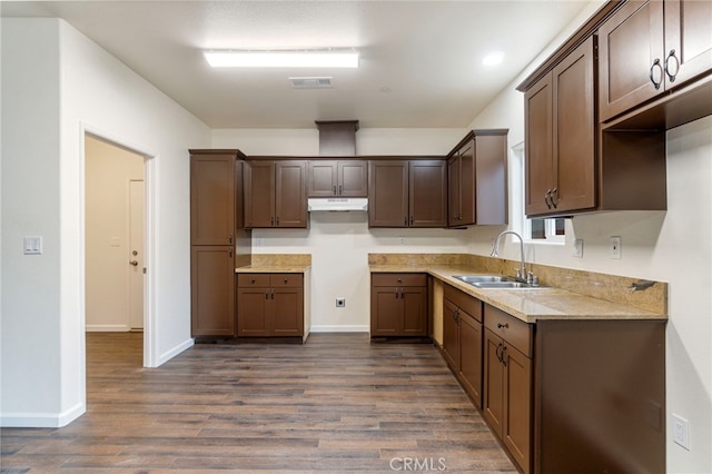 kitchen with dark hardwood / wood-style floors, dark brown cabinets, light stone countertops, and sink