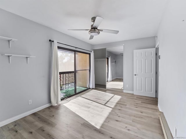 empty room featuring ceiling fan, light wood-type flooring, and baseboard heating