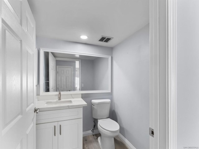 bathroom with hardwood / wood-style flooring, vanity, and toilet