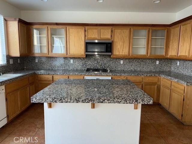 kitchen with tile patterned flooring, tasteful backsplash, dark stone counters, and a kitchen island